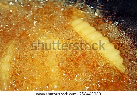 French fries cooking and bubbling in a deep fryer filled with oil