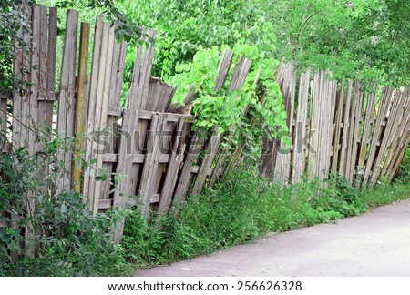 An old worn wooden fence falling over and in need of repair