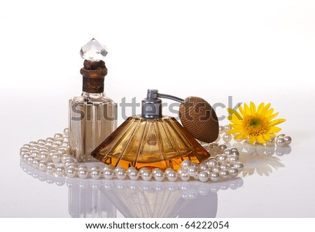 VINTAGE PERFUME BOTTLES, PEARLS AND A YELLOW FLOWER ARRANGEMENT ISOLATED ON WHITE