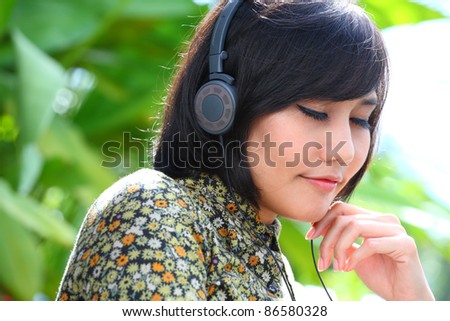 female relaxing with music from ear pad headphone.