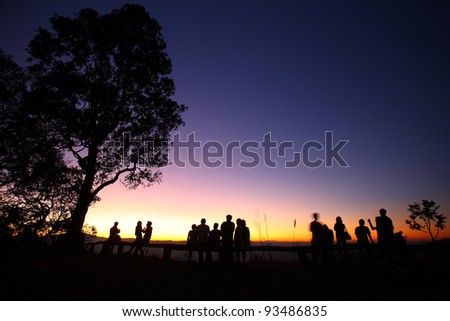 sunset view with tree and people silhouettes.