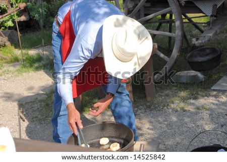 A Cowboy Cooking Biscuits in a Dutch Oven