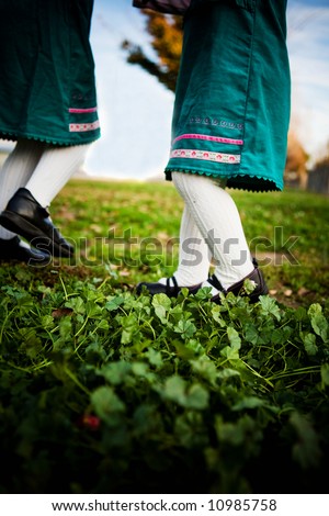 Two young girls dancing in the grass - feet .  bottom half, no face showing