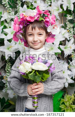 Beautiful little girl near the wall of flowers