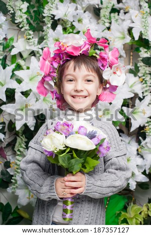 Beautiful little girl near the wall of flowers