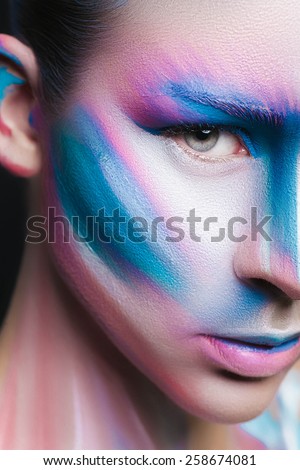 Beautiful fashion woman with bright color face art and body art. Paint on face. Creative portrait