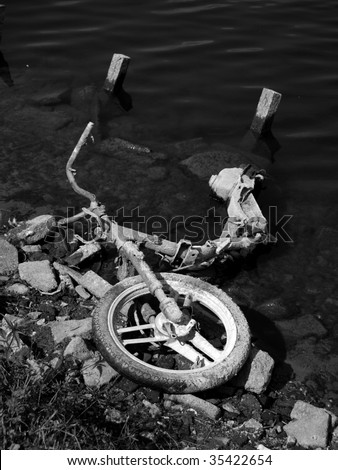 Black and white image of a motorcycle dumped in a pond