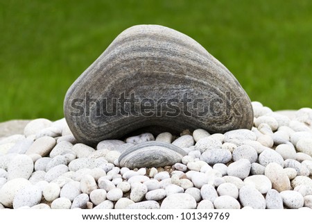 Two natural rock elements, one large and one small, of Zen garden are placed to capture similarity and harmony; layers in rock are visible;