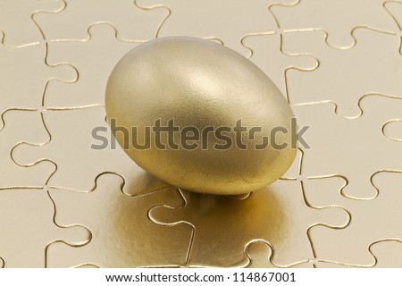 Golden nest eggs sits on metallic gold puzzle; savings is the key to the financial and business puzzle.
