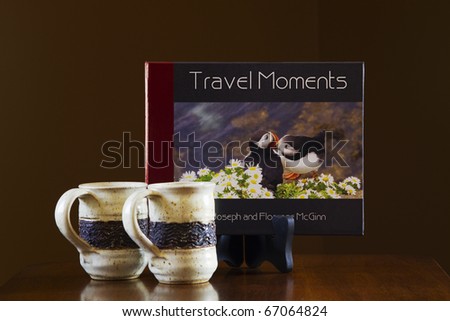 Photo book of travel moments and two mugs of coffee on a coffee table and ready to be shared