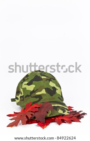 Hunter\'s cap sits on red leaves with copy space above in vertical orientation image.
