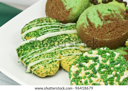 Saint Patrick\'s Day cookies with green sprinkles, green dough, and a shamrock shaped sugar cookie on a white plate