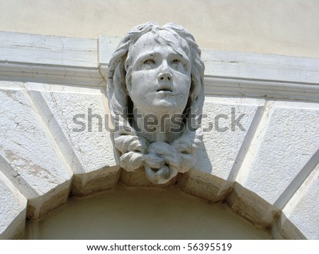 Stone head of a girl with her hair tied under her chin on a Medieval Arch