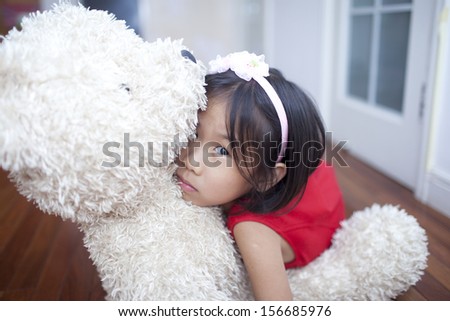 Chinese cute girl with teddy bear  at home