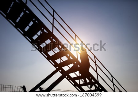 people climbing stairs in sunset on sky background