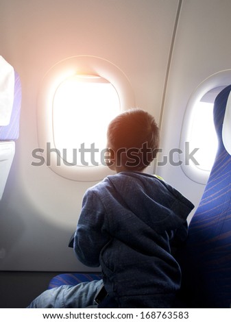 Asian Boy Looking Outside Of Airplane Window