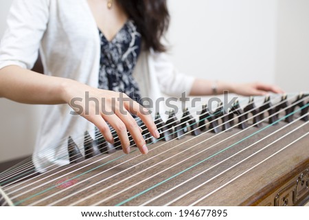 Chinese artist playing Guzheng, a Chinese old 21-or 25-stringed plucked instrument