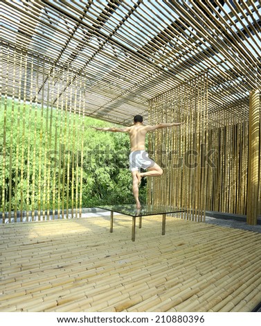 Young man is practicing yoga in bamboo house on green plants background