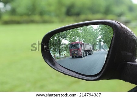 big truck reflected in rear mirror on highway