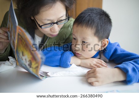 Asian mother reading book for son
