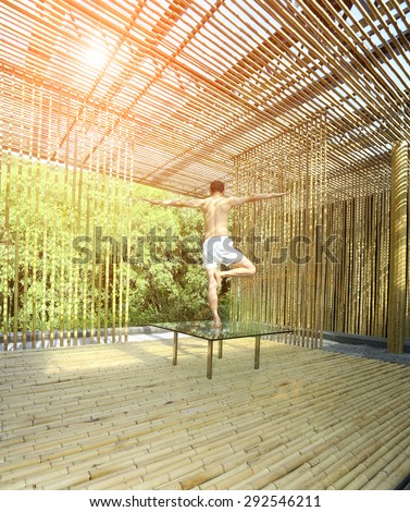 Young man is practicing yoga in bamboo house on green plants background