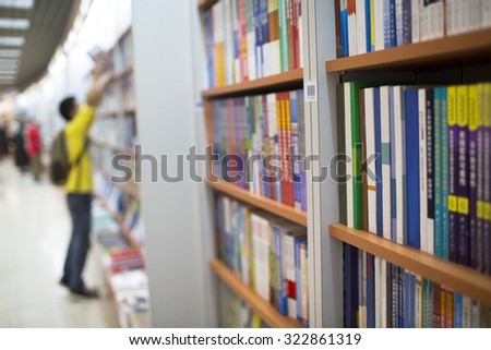 Students reading while standing up in a library ( book name and logo has been removed)