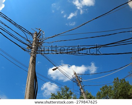 Poles with a lot of wires and electric lamps lighting against a blue sky with wide angle distortion view