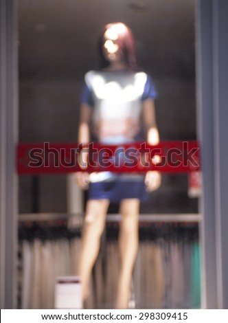 Defocused and blur female mannequin dressed in a glass shop window was blurred for use as background