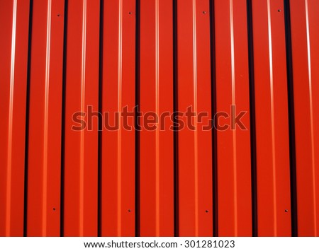 Red metal corrugated sheet metal with longitudinal stripes and striped shadows illuminated bright sun to use as background