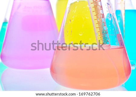 Volumetric laboratory glassware containing colored liquids isolated over white background