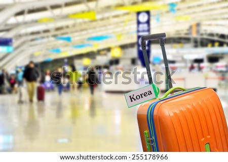 Korea. Orange suitcase with label at airport.