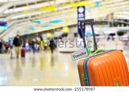 Traveler Orange suitcase with label at airport Traveler Orange suitcase with label at airport