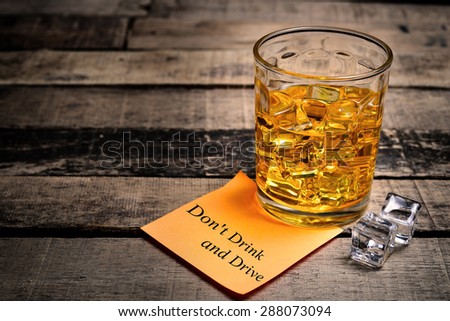 Whiskey in light pool and Don\'t Drink and Drive note on brown table