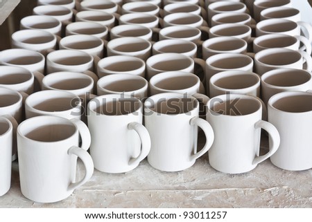 Ceramic mugs in racks in ceramic work shop