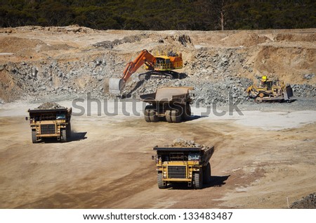 Large yellow trucks used in modern mine Western Australia. Digger fills empty trucks  which transport ore from the open cast mine.