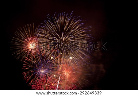 4th July fireworks explode in sky. Purple and orange burst.