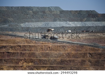 Yellow trucks drive out a dirt road in an open cast mine in New South Wales, Australia. Barrick Cowal Gold Mine.