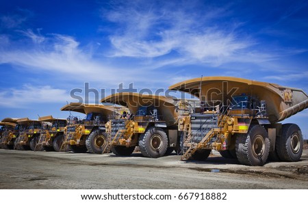 Massive yellow excavation trucks lined up. Used for transporting mine ore. Industrial transportation. All logos removed.