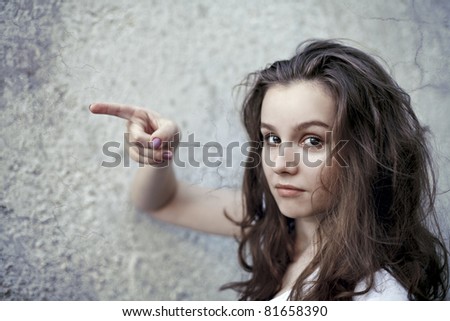 portrait of beautiful young woman pointing her finger at something