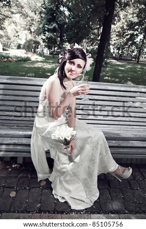 portrait of a bride, sitting alone on a bench and drinking alcohol