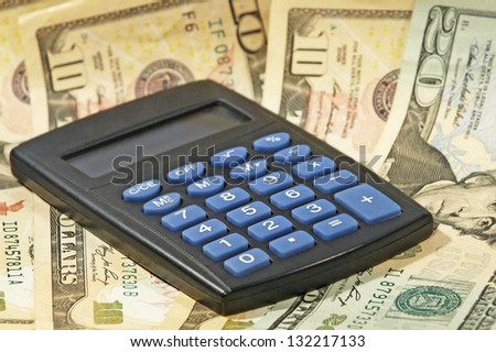 Electronic calculator and USA dollar banknotes taken closeup.