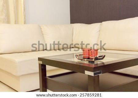 Coffee table taken closeup and white corner leather sofa .