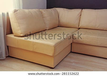 Modern beige corner leather sofa in livingroom taken closeup.