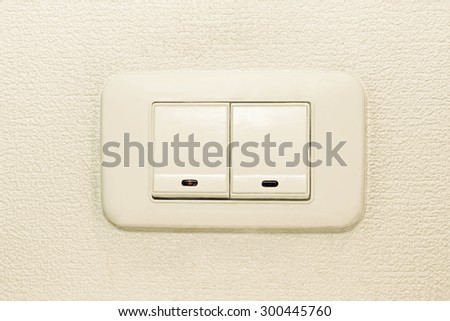 Light switch on beige wall background taken closeup.