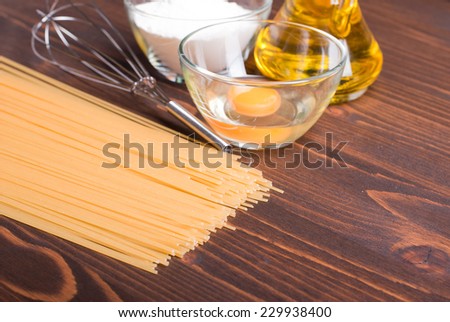 raw pasta with spices and ingredients on a brown wooden table
