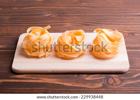 pasta raw three circles in a row on a small cutting board on a light table korrichenvom side view