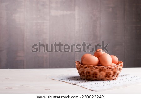brown eggs in a wicker basket on a light wooden table and a side view