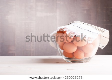 brown eggs in a large glass bowl on a light wooden table side view