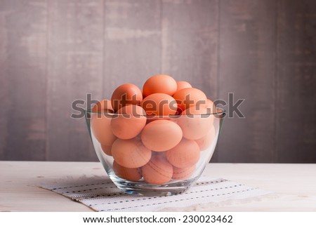 brown eggs in a large glass bowl on a light wooden table and a side view