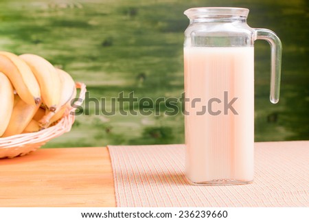 banana juice in the decanter on a yellow table with a napkin on zalenom background bananmi side view